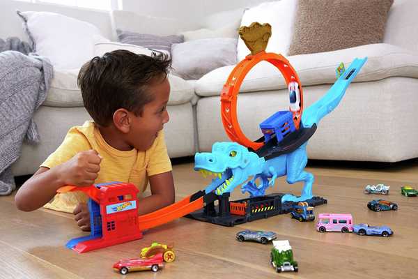 A toddler playing with a Hot Wheels City T-Rex Chomp Down Playset.